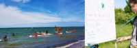 Surfer im Meer und Junge beim Surfunterricht