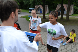 Kampfsportcamps - Mädchen haut in Bruchtestbrett im Kinderferienlager