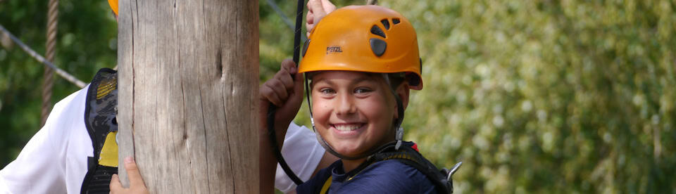 Kind lacht beim Klettern im Adventure Camp