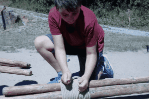 Junge schnürrt Holz zusammen