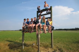 Kinder sitzen auf überdimensionalen Stuhl aus Holz