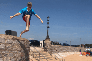 Junge springt auf Mauer am Strand