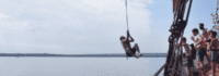 Junge schwingt mit Tau von Boot