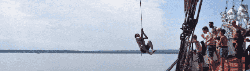 Junge schwingt mit Tau von Boot
