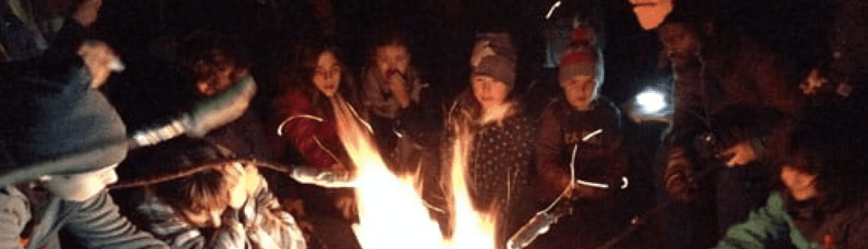 Kinder backen Stockbrot am Lagerfeuer