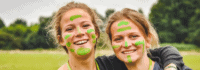 zwei lachende Mädchen mit grüner Farbe im Gesicht