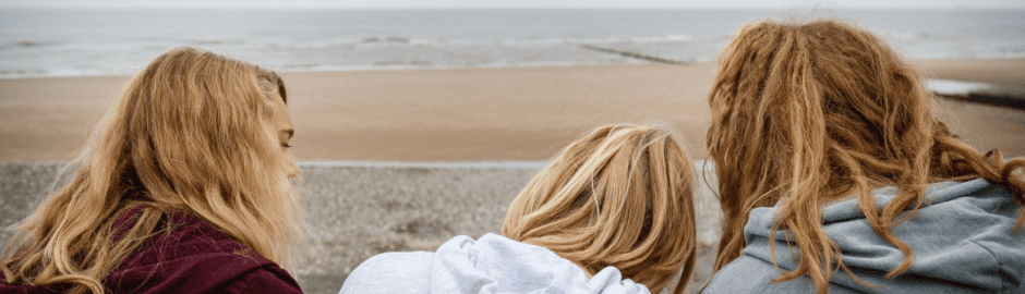 drei Mädchen sitzen am Strand