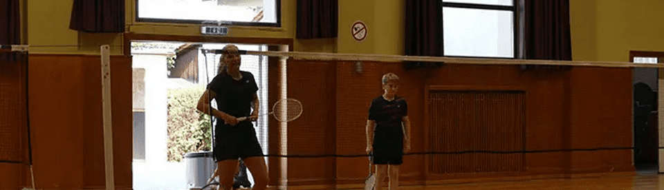 Trainerin und Junge hinter Bdmintonnetz