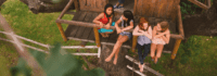 Mädchen sitzen in einem Baumhaus