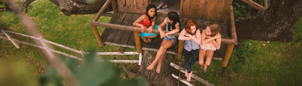 Mädchen sitzen in einem Baumhaus