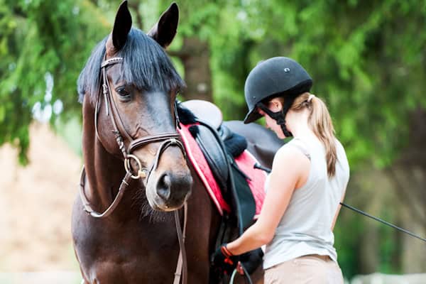 Mädchen sattelt Pferd im Französischcamp mit Reiten in Hambach