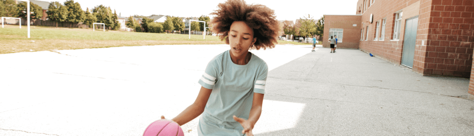 Mädchen spielt mit pinkem Basketball