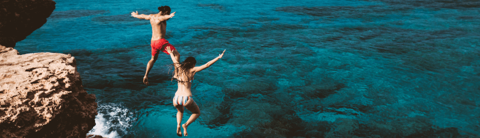 Jugendliche springen von Fels ins Meer