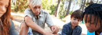 Kinder und Jugendliche sitzen zusammen im Camp