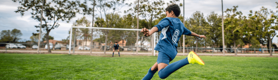 Junge spielt Fußball und zielt aufs Tor