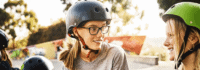 Mädchen mit Fahrradhelmen lächeln sich an