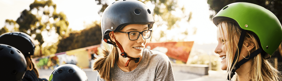 Mädchen mit Fahrradhelmen lächeln sich an