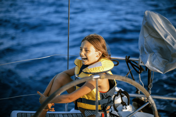 Kind lacht im Feriencamp mit Segeln