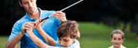 Erwachsener erklärt Golfschlägerhaltung, während andere Kinder zuschauen