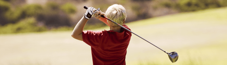 Junge holt zum Golfschlag aus