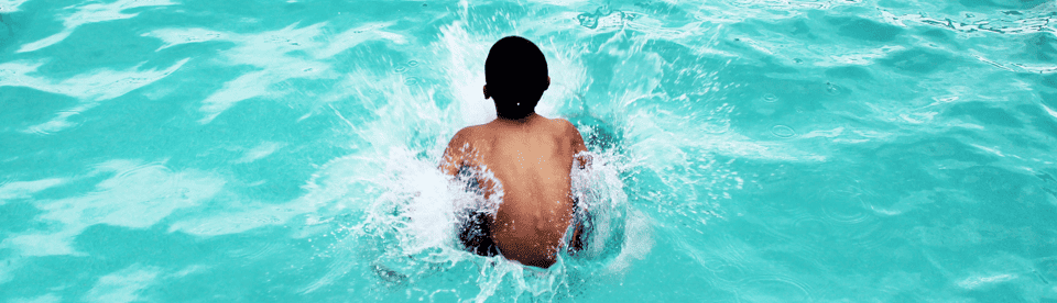 Junge springt ins türkise Wasser