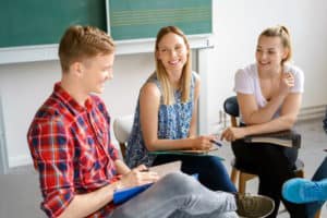 Englischcamp Wernigerode: Drei Jugendliche lachen zusammen beim lernen im Klassenzimmer