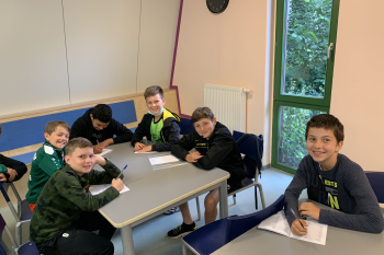 6 Kinder sitzen zusammen am Tisch zum Deutsch lernen