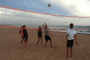 Kinder spielen Volleyball am Strand im Sommerferienlager