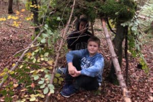 Jungen sitzen im selbstgebauten Unterschlupf im Feriencamp am Ammersee