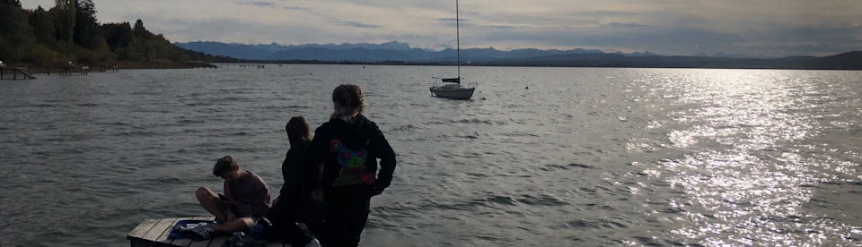 Kinder sitzen am Steg des Ammersees