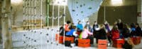 Kinder sitzen vor Kletterwand