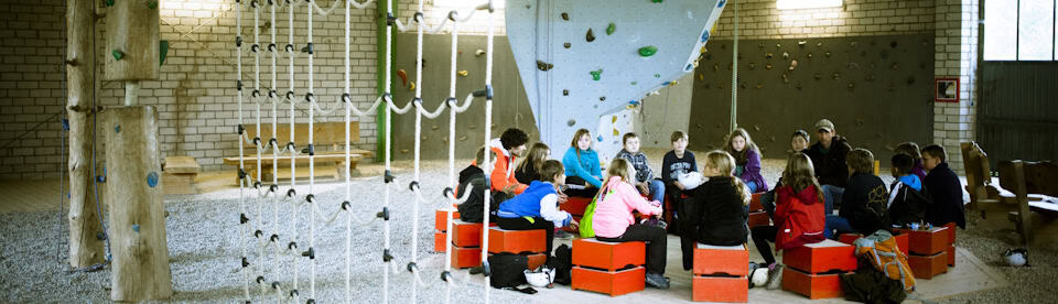 Kinder sitzen vor Kletterwand