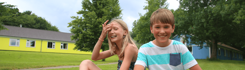 Kinder sitzen im Gras im Feriencamp