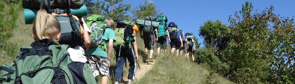 Einige Abenteurer sind mit großen Rucksäcken auf ihrer Wanderung unterwegs im Abenteuermix Frankreich