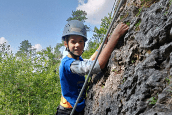 Junge mit Helm klettert am Fels
