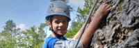 Junge mit Helm am Fels