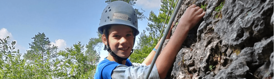Junge mit Helm am Fels