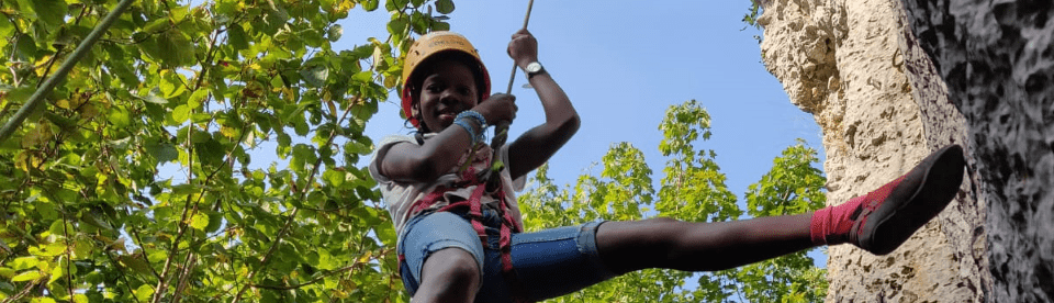 Mädchen mit Helm hängt im Seil