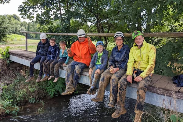 Familie sitzt mit schlammigen Hosen auf einer Brücke
