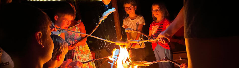 Gruppe am Stockbrot machen über dem Lagerfeuer