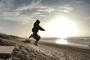 Kind springt am Strand im Englisch Camp Sylt