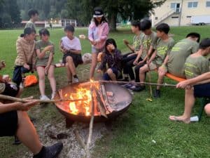 Sportcamp mit Handball, Kinder sitzen um ein Lagerfeuer 