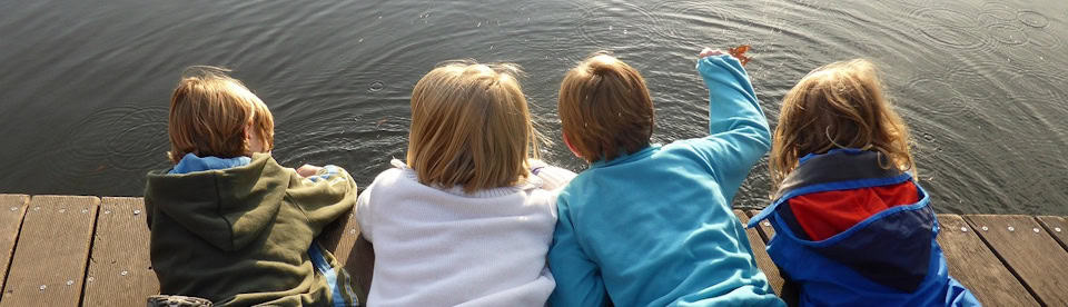 Kinder liegen auf einem Steg am See