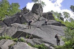 Teilnehmer klettern am Kletterfelsen