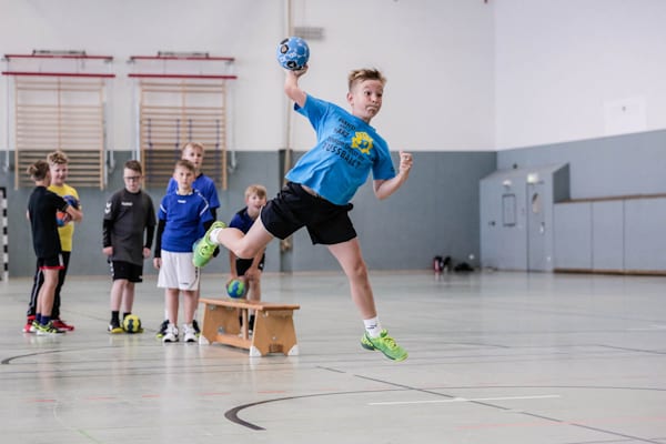 Ein Junge macht einen Sprungwurf mit einem Handball in der Hand