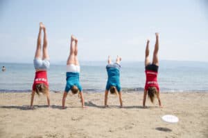 Kinder die einen Handstand am Meer machen