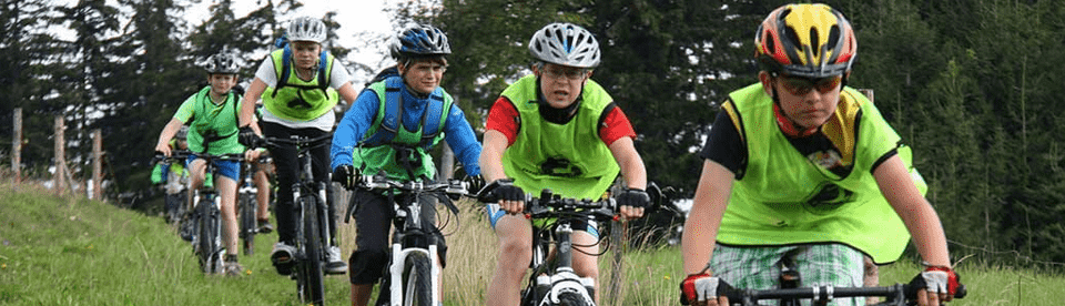 Gruppe von Mountainbikern fährt in einer Reihe über Wiese