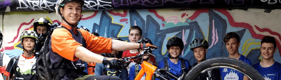 Mountainbiker macht Wheelie vor Gruppe