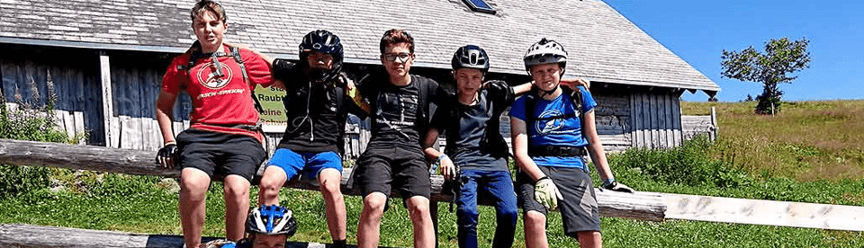 Gruppe von Jungs sitzt auf Holzbalken