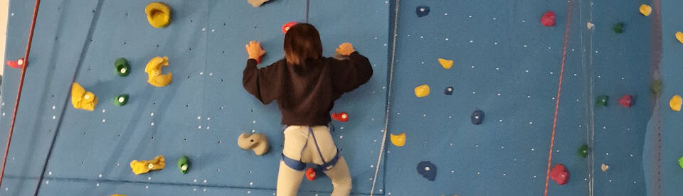 Ein Mädchen am Klettern an der Kletterwand
